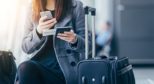 Woman holding smartphone and passport at airport