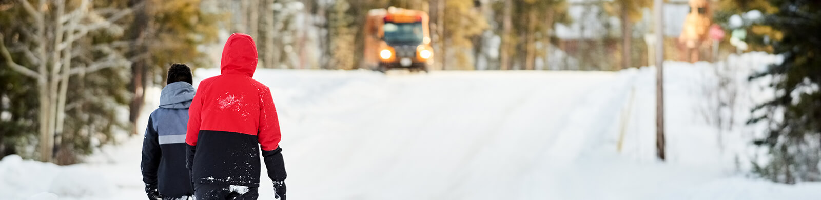 Two people walking up a winter road.