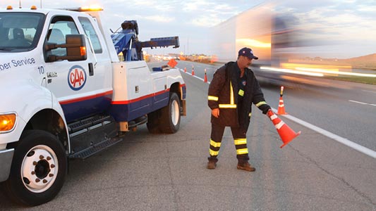 A CAA Manitoba tow truck driver placing safety cones on the road.
