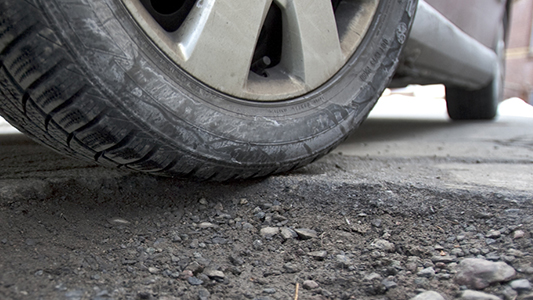 A vehicle driving over a filled pot hole.