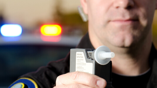 A police officer holding a breathalyzer.