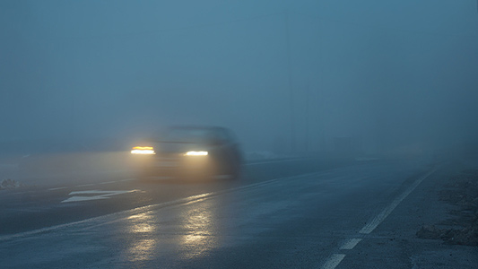 Vehicle driving in thick fog at night.