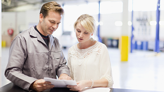  An auto mechanic going over paperwork with a client.