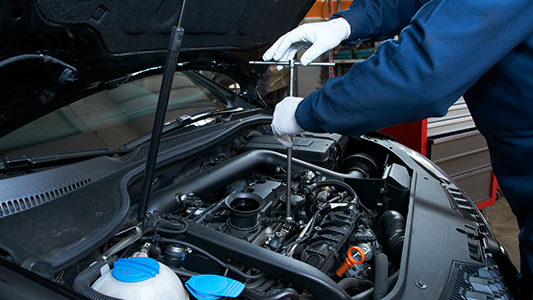 An auto mechanic working under the hood of a car.