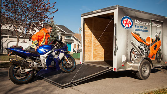 A CAA tow truck driver loading a motorcycle into the CAA motorcycle rescue trailer.