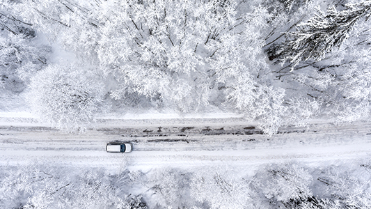 A car driving on a road in the winter time.