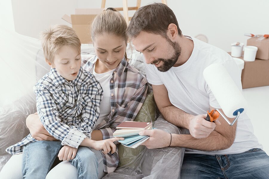 Mom, dad & son sitting on a sofa looking at paint samples.