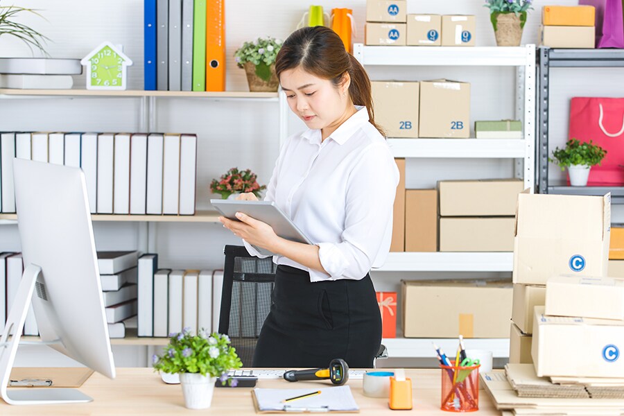 A woman working on her iPad in a home office.