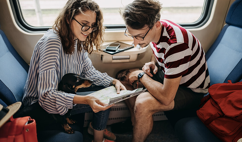 Couple sitting-in a train looking at a map.