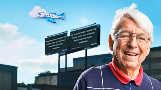 Man standing in front of building with airplane in sky