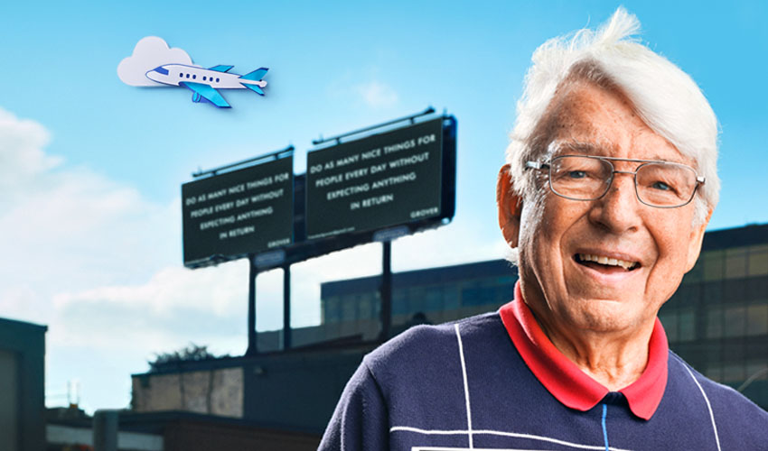 Man standing in front of building with airplane in sky