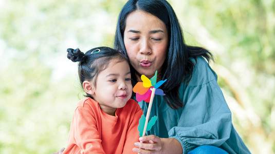 Mom and child playing outside with a toy.