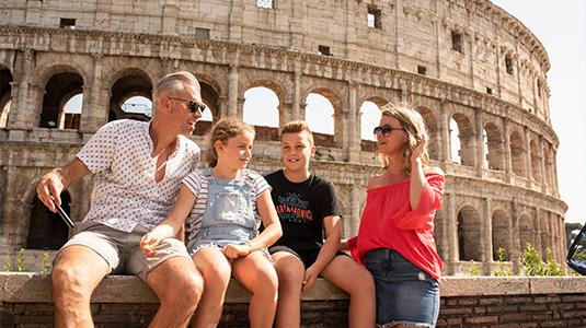 Family sitting in front of the Rome Colosseum