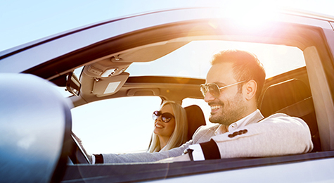 A couple driving with the windows down.