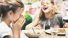 A couple of kids laughing during dinner time.