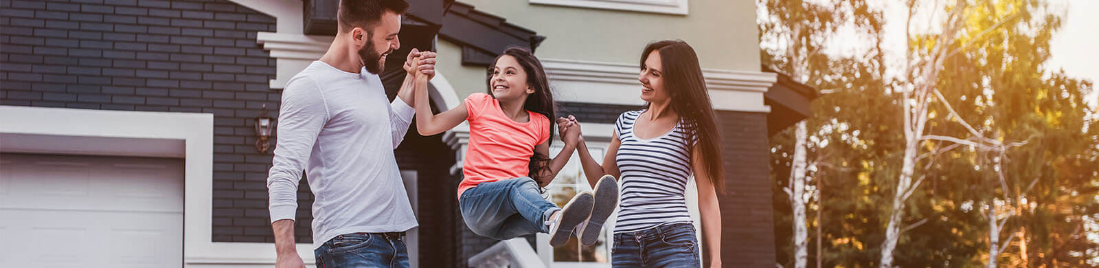 A family of three playing in front of their house.