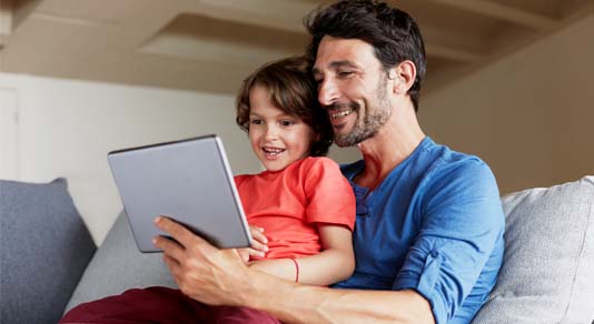 Father and son using digital tablet on sofa