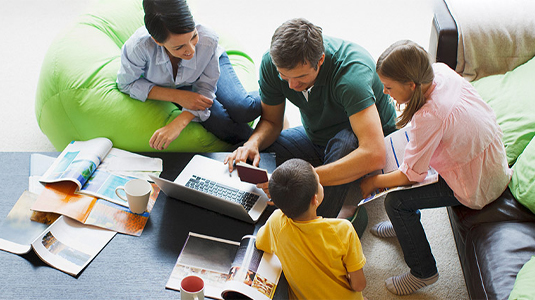 Family gathered around a laptop in the living room