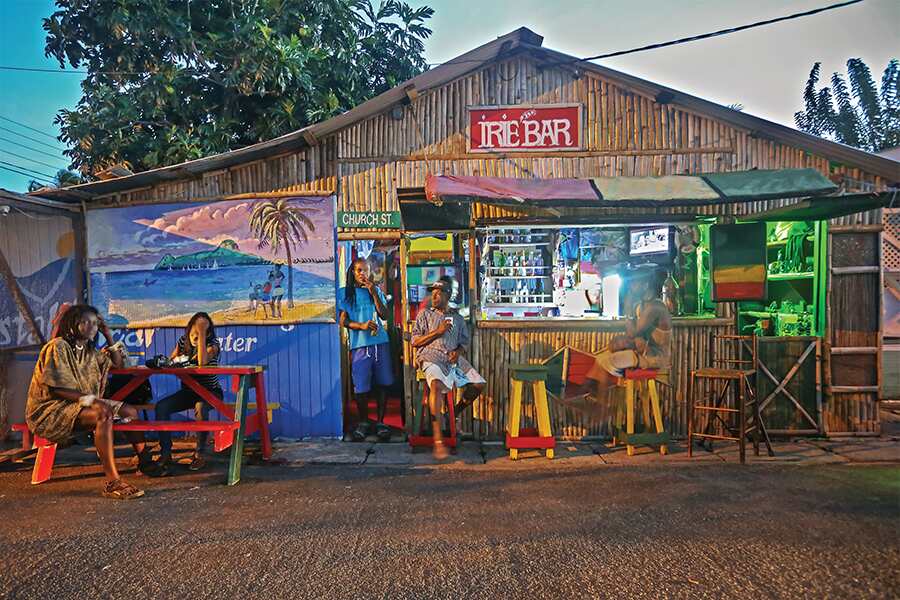 Photo showing storefront of wooden building decorated with colourful scenes painted on the wall.
