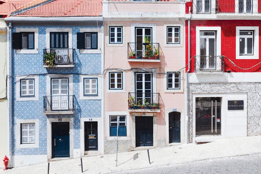 Image showing three colourfully-painted stone houses lining a street in Lisbon.
