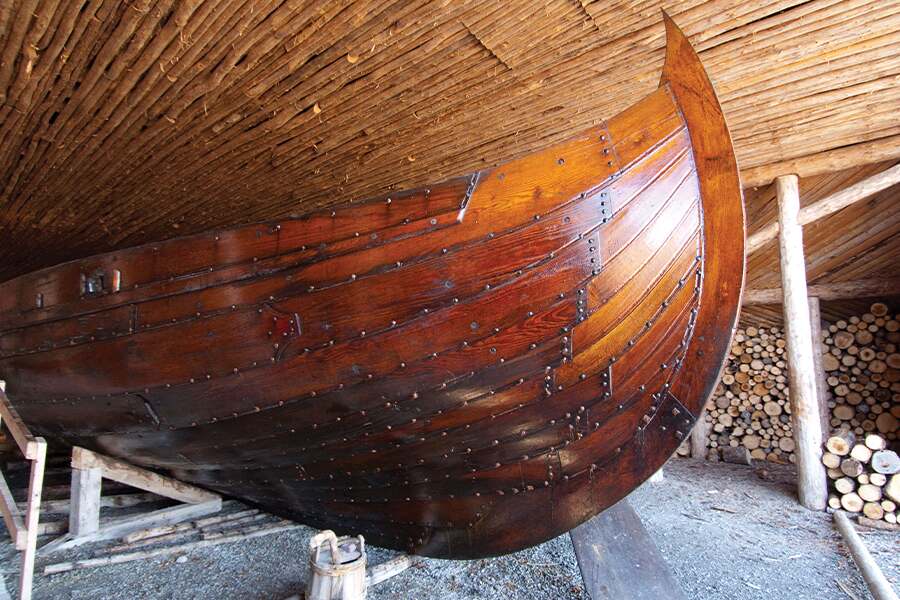 Photo showing the large hull of a recreated Viking longboat inside a building.
