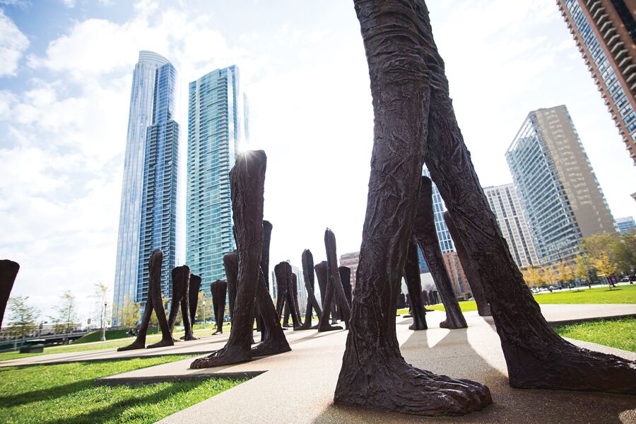 Photo showing Chicago park space with large scultures of legs and feet in the foreground and background.