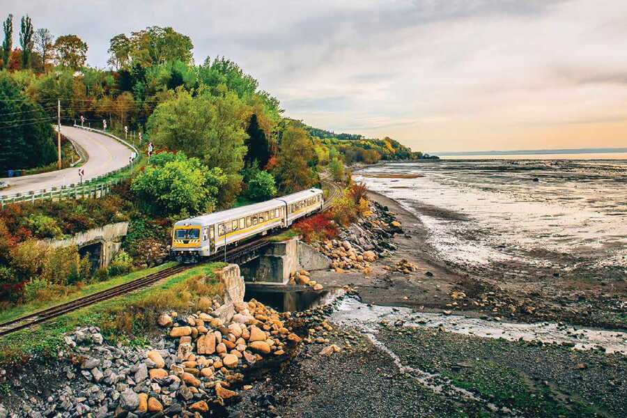 Image showing a train crossing a small bridge on a rail line running beside a river.