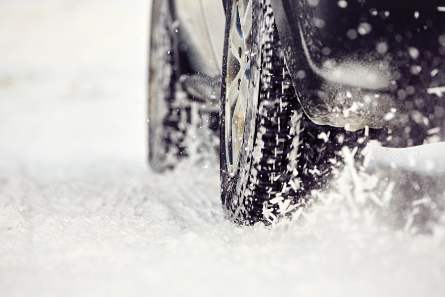 Photo showing closeup of winter tires churning up snow on a snow-covered road.