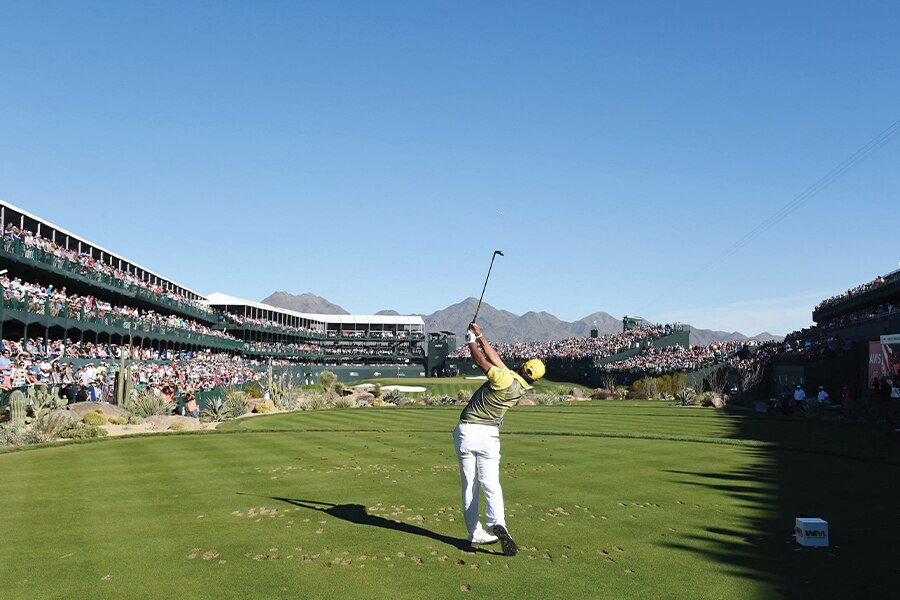 Image showing a golfer hitting the ball beside a golf course viewing stand crowded with spectators.