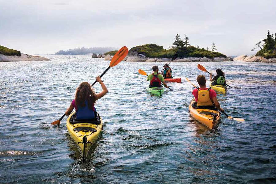 Photo showing several kayaks being paddled toward small island outcroppings in the distance.