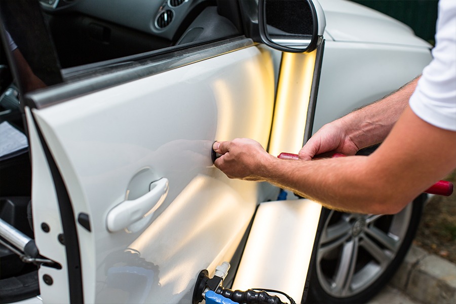 Image showing closeup view of technician repairing dent in car door.