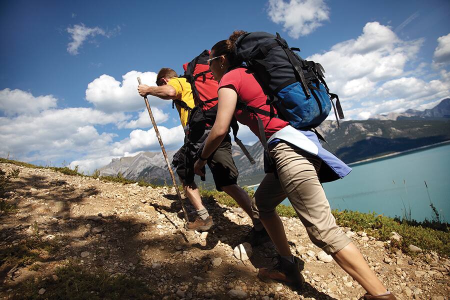 Image showing two hikers with backpacks climbing rocky slope in the mountains.