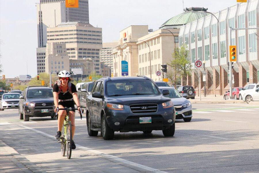 Photo showing cyclist on busy urban street with cars.
