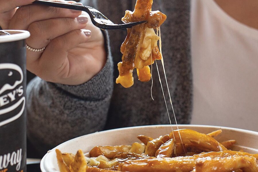 Image showing a hand raising a fork full of gravy-and-cheese infused french fries.