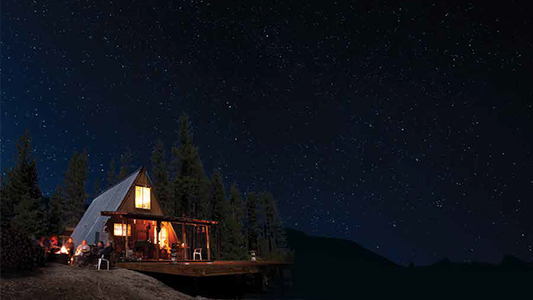 Photo showing a chalet-style cabin lit up at night.