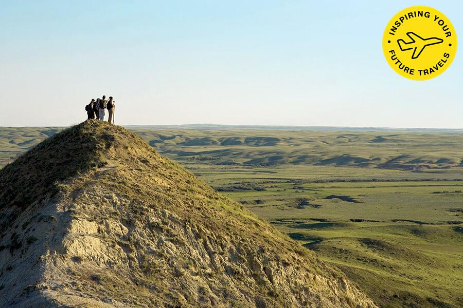 Photo shows a group of hikers standing atop a small hill overlooking the Saskatchewan prairie.