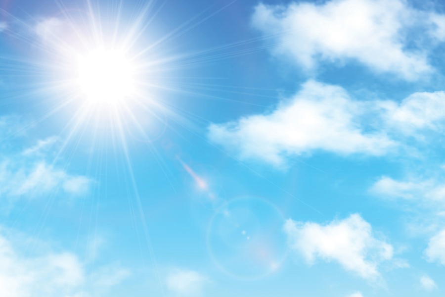 Photo showing a bright sun against a light blue sky with cumulus clouds.