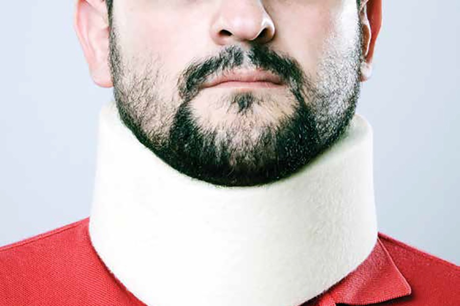 Photo showing lower face of bearded man wearing white neck brace.
