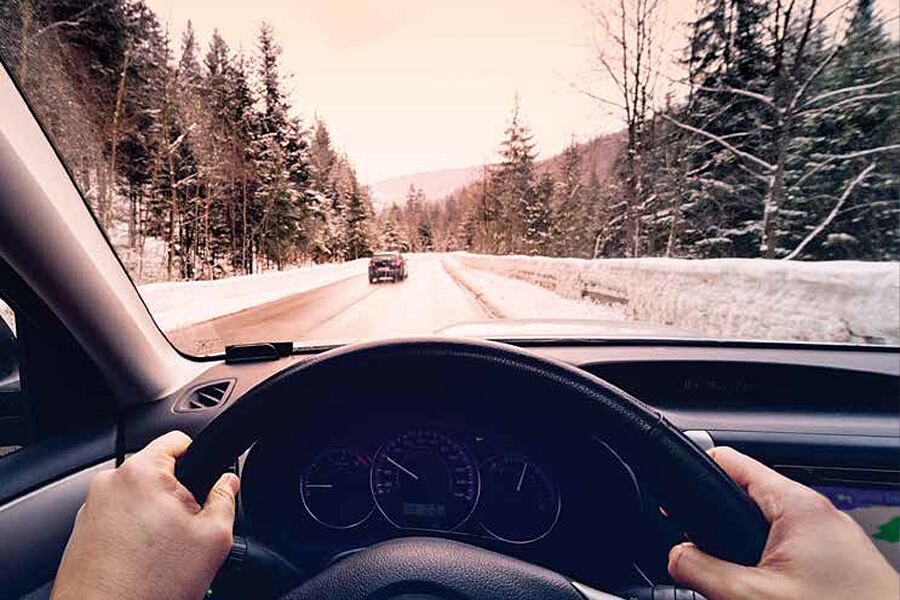 Image showing drivers-eye view outside front of windshield of highway with car ahead in winter landscape.