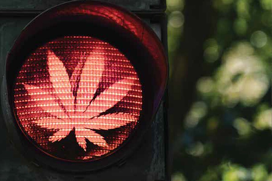 Image showing the red signal of a traffic light with a marijuana leaf superimposed on the light.