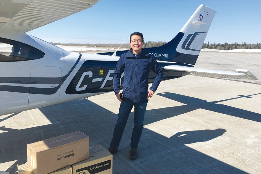 Image showing CAA Club Group CEO Jay Woo standing beside light aircraft on tarmac with cardboard boxes in the foreground.
