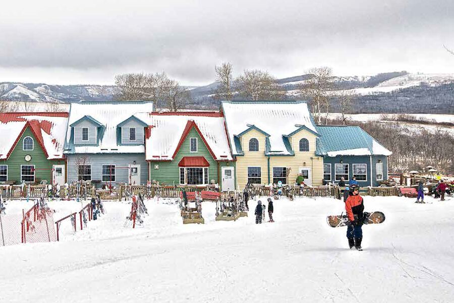 Image showing people playing in the snow with a row of colorful homes in the background.