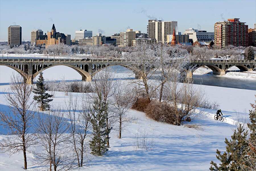 Image showing view of downtown Saskatoon in background with road bridge across a frozen, snow covered river.