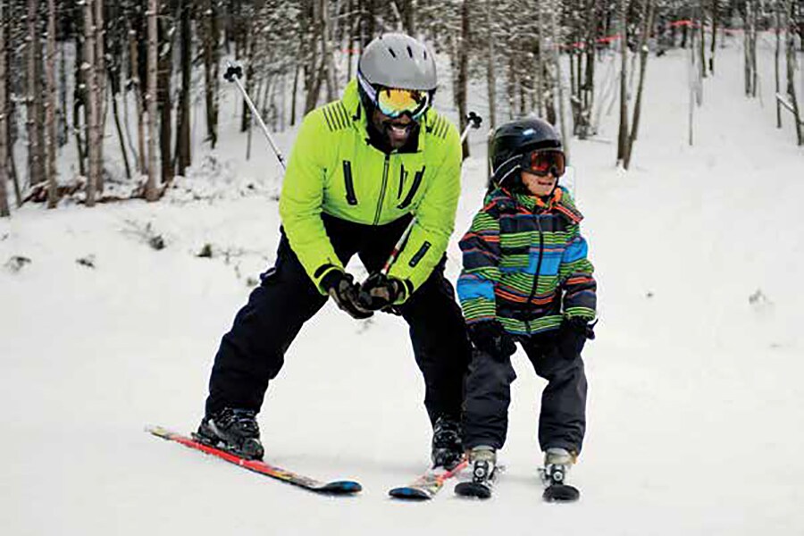 Image showing father and yound daughter on skis, with winter woods in the background.