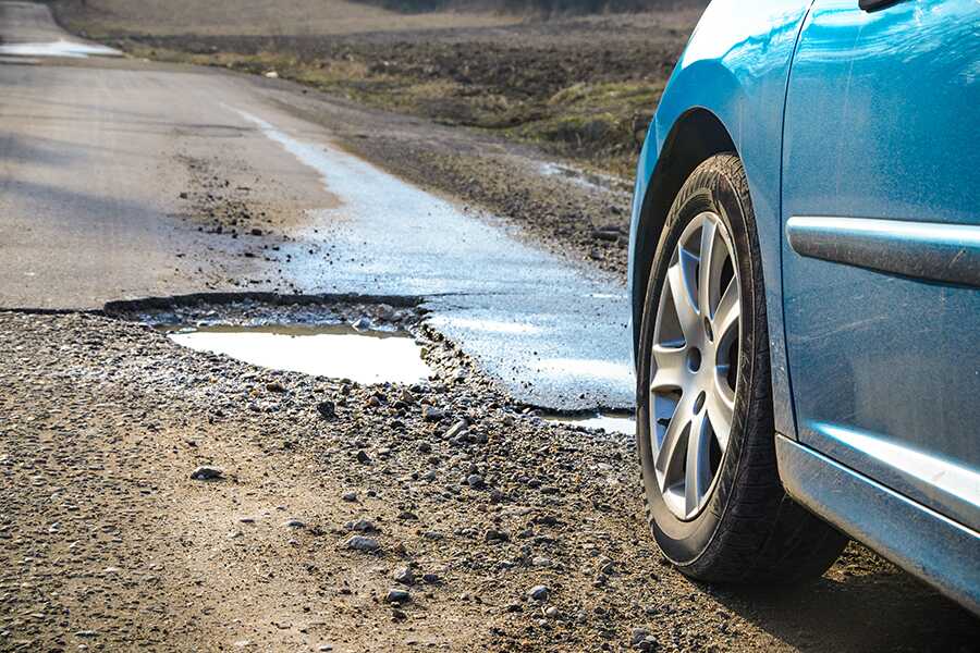 Image showing a closeup of a car tire about to hit a pothole.