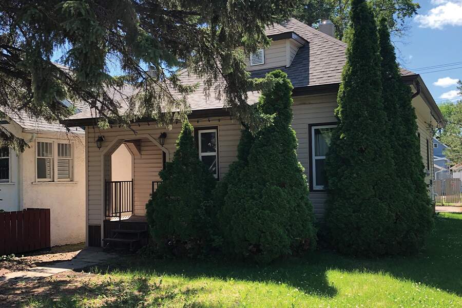 Image showing the exterior of a small home with trees in front.