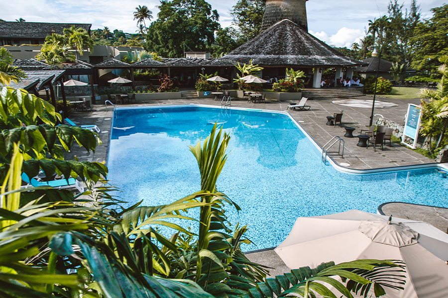 Image of a hotel swimming pool with large umbrellas around it.
