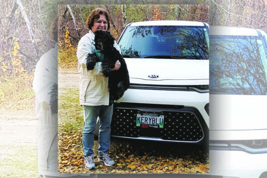 Image showing woman holding dog and standing in front of her car.