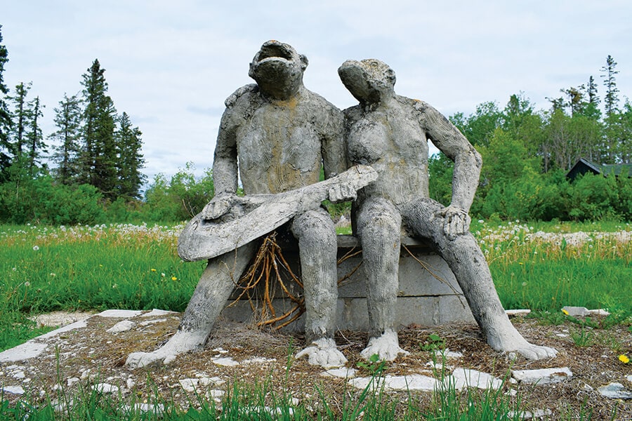 Image showing concrete statue of two ape-like creatures playing a guitar and singing.
