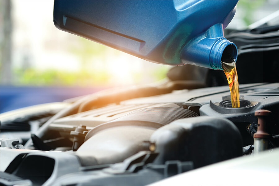 Image showing a blue jug of motor oil being poured into a car engine.
